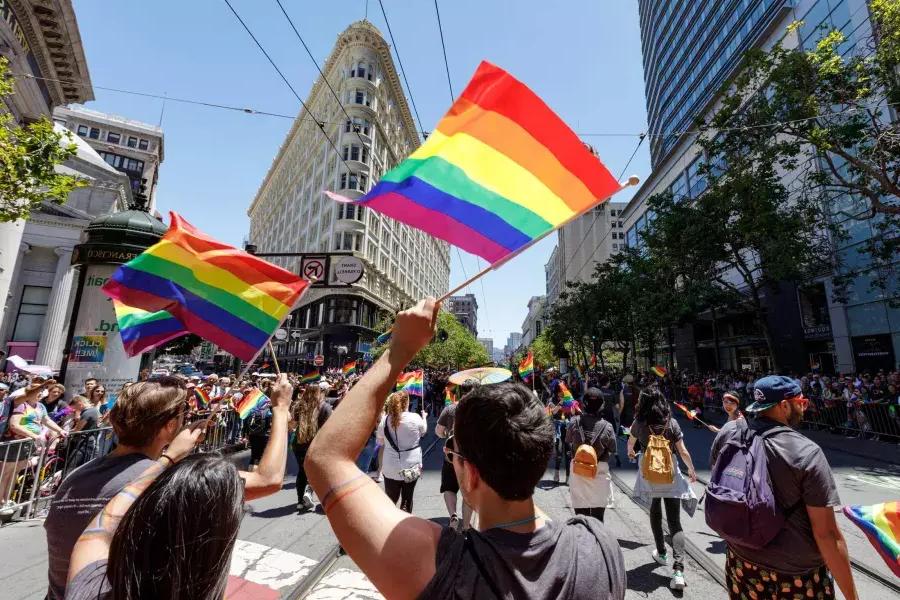 Les gens qui marchent dans le défilé de la fierté de San Francisco brandissent des drapeaux arc-en-ciel.